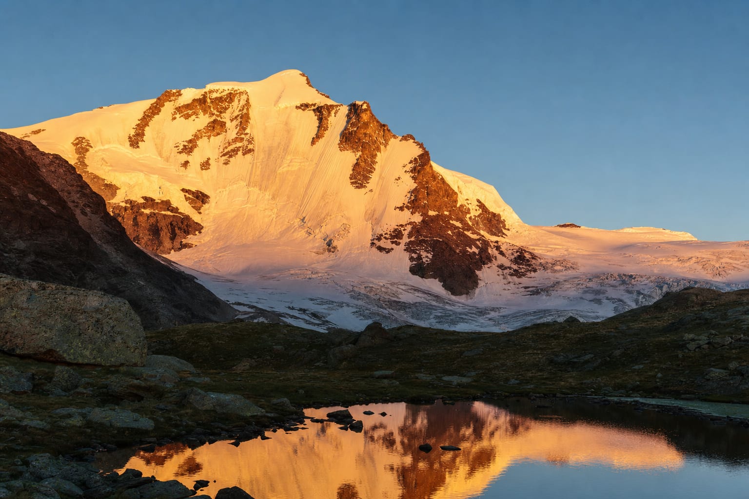 Alpenglow on the Gran Paradiso massif mirrored in an alpine lake