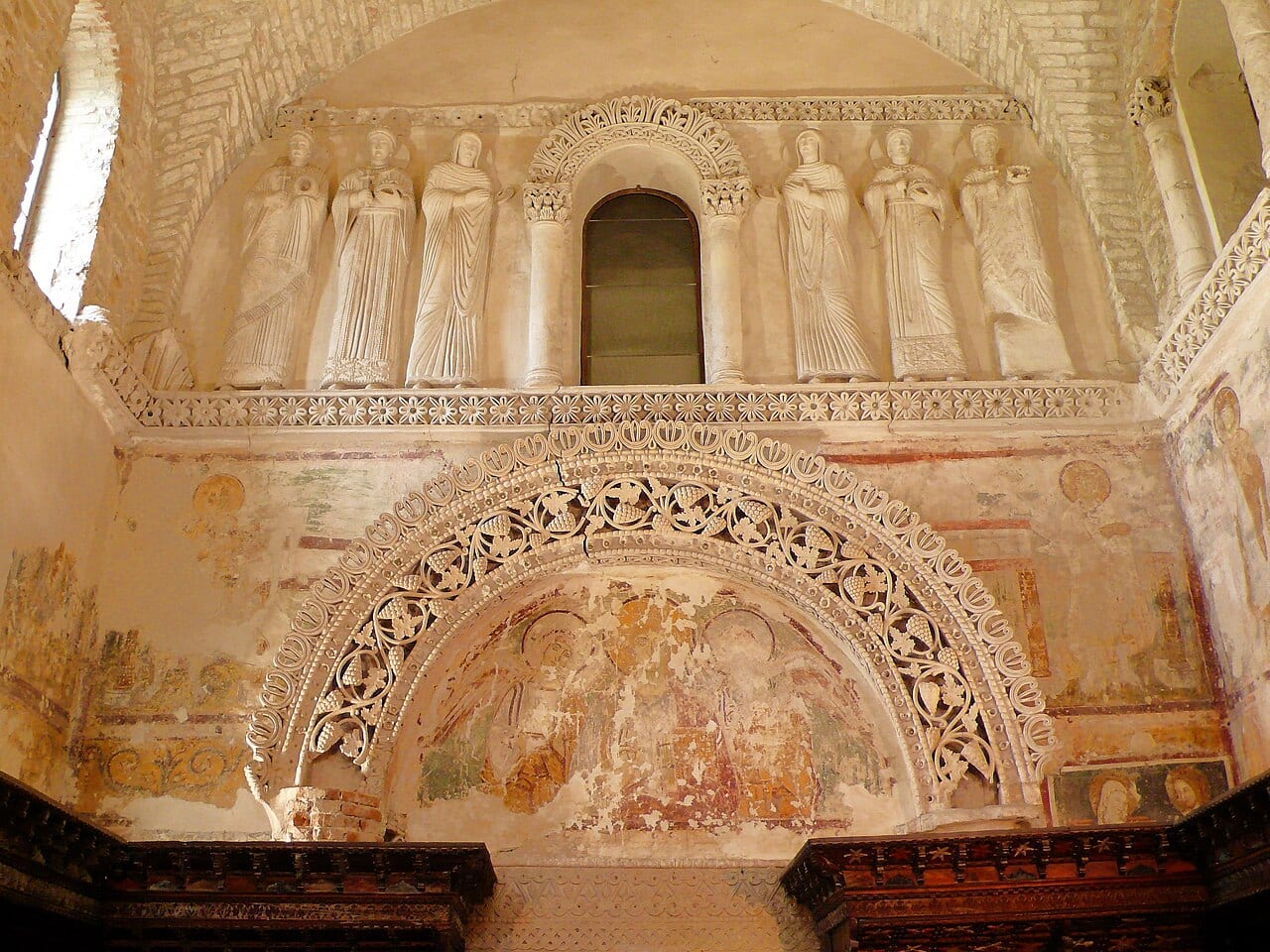 The stucco saints of the Tempietto Longobardo above its frescoed arch, Cividale