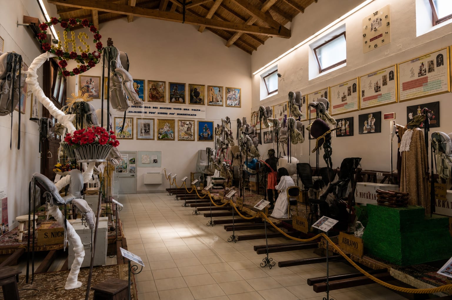 Inside the Misteri Museum in Campobasso, the steel ingegni that carry costumed children above the Corpus Domini procession stand in rows beneath the timber roof