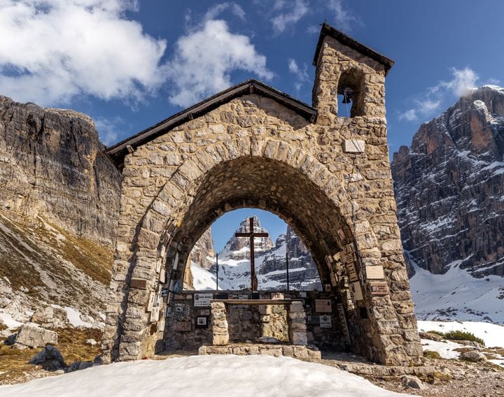 A stone arch framing the Brenta Dolomites near Madonna di Campiglio
