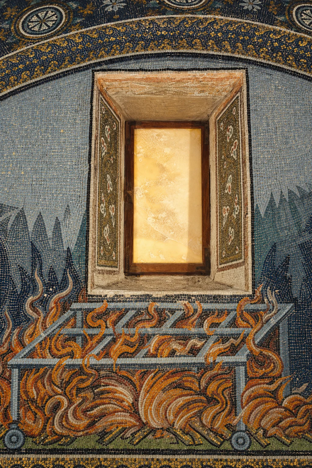A glowing rectangular alabaster window with mosaic-lined reveals above a metal grid surrounded by orange flames on a blue mosaic field.