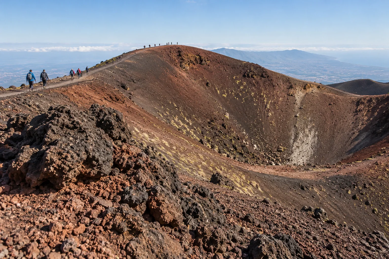 Hikers walking the rim of an extinct cinder cone on Etna