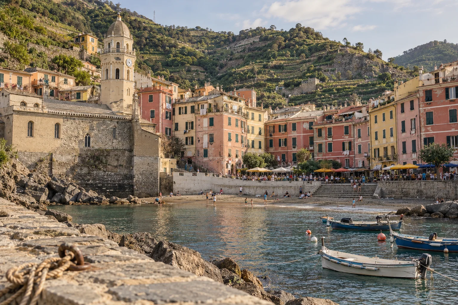 Pastel houses and cafe umbrellas on Piazza Marconi facing the small beach in Vernazza