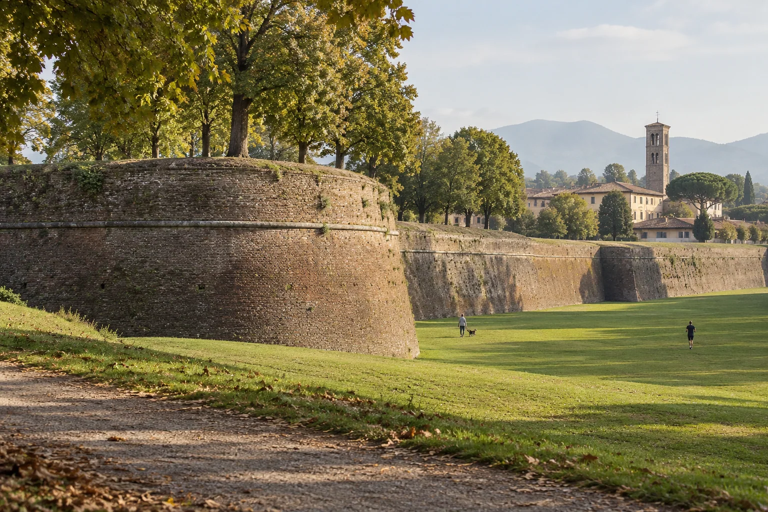 A rounded brick bastion of the walls of Lucca seen from the lawn below
